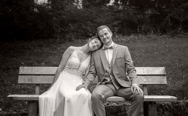 Brautpaar sitzt glücklich zusammen auf Parkbank in Aachen